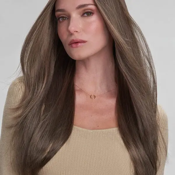 Woman with long brown hair, neutral expression.